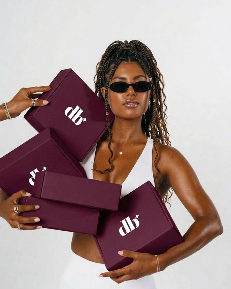 Woman holding multiple purple boxes with 'didi beauty' logo against a white background